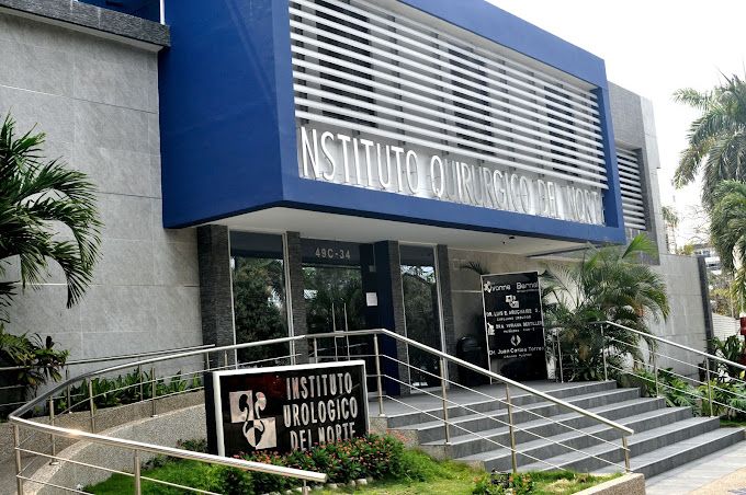 Médico urólogo en consulta con paciente adulto en clínica especializada de Barranquilla, revisando resultados de examen urológico sobre escritorio clínico