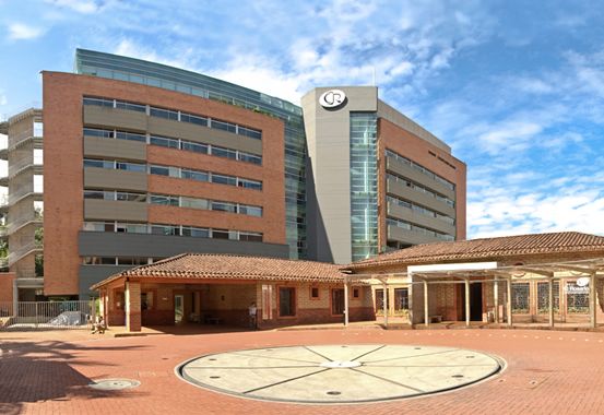 Pasillo interior de la Clínica El Rosario en Medellín con personal médico en uniforme atendiendo a un paciente en silla de ruedas frente a consultorios especializados