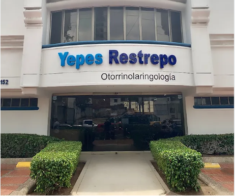Médico otorrinolaringólogo revisando los oídos de un paciente adulto en una sala de consulta especializada equipada con instrumentos de diagnóstico en una clínica de Barranquilla
