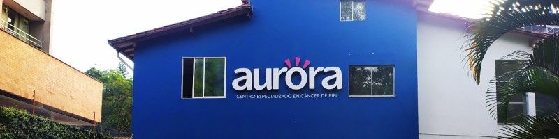 Médico dermatólogo oncólogo revisando lesiones en la piel de un paciente adulto en una consulta especializada de la Clínica Aurora en Medellín, Colombia