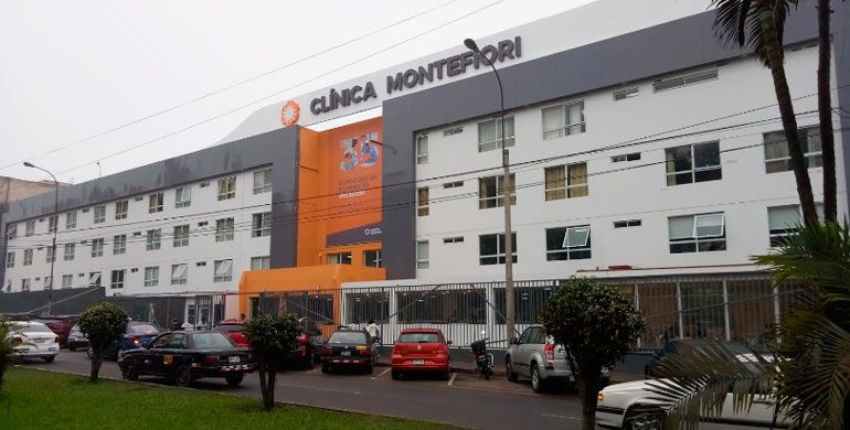 Fachada moderna de la Clínica Montefiori en el distrito de La Molina, Lima, con acceso vehicular y peatonal visible durante el día