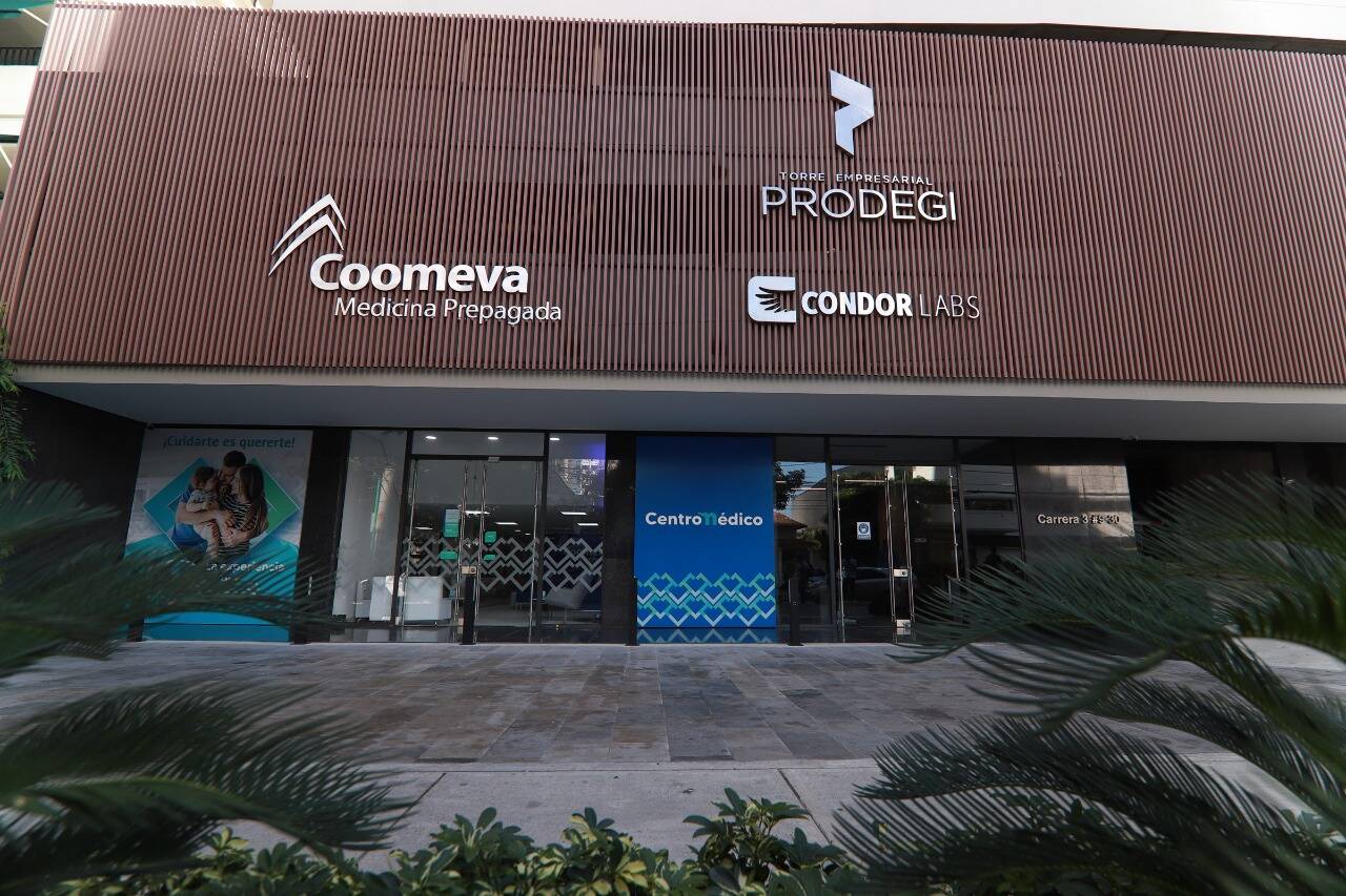 Fachada de una sede de Coomeva Medicina Prepagada en Colombia con paciente ingresando a consulta médica especializada