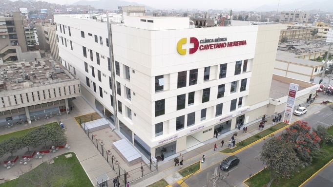 Fachada moderna de la Clínica Cayetano Heredia en San Martín de Porres, Lima, con acceso vehicular y señalización institucional visible