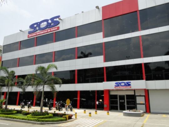 Fachada principal de una sede de EPS SOS en Colombia, con personal administrativo atendiendo afiliados en ventanillas de servicio al usuario
