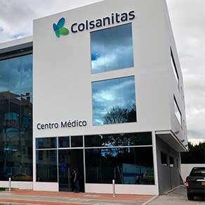 Fachada de una clínica Colsanitas en Colombia con el logo institucional visible y pacientes ingresando al área de consulta externa