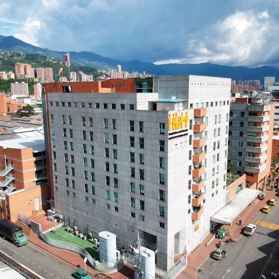 Entrada principal del Hospital General de Medellín con personal médico uniformado atendiendo pacientes en el área de urgencias