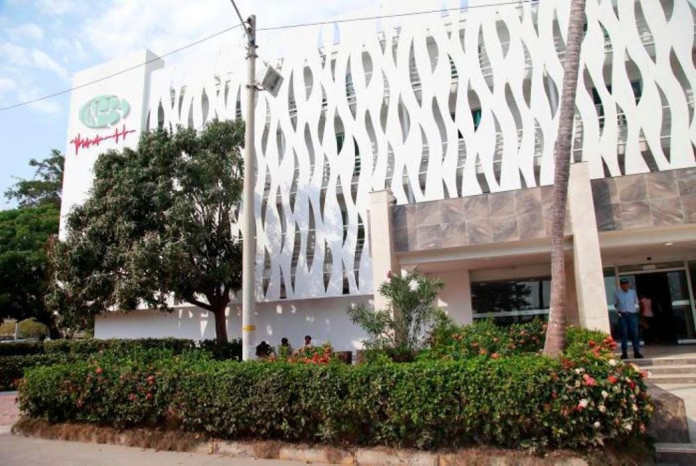 Fachada moderna del Nuevo Hospital de Bocagrande en el sector de Castillo Grande, Cartagena, con personal médico en la entrada principal durante atención diurna